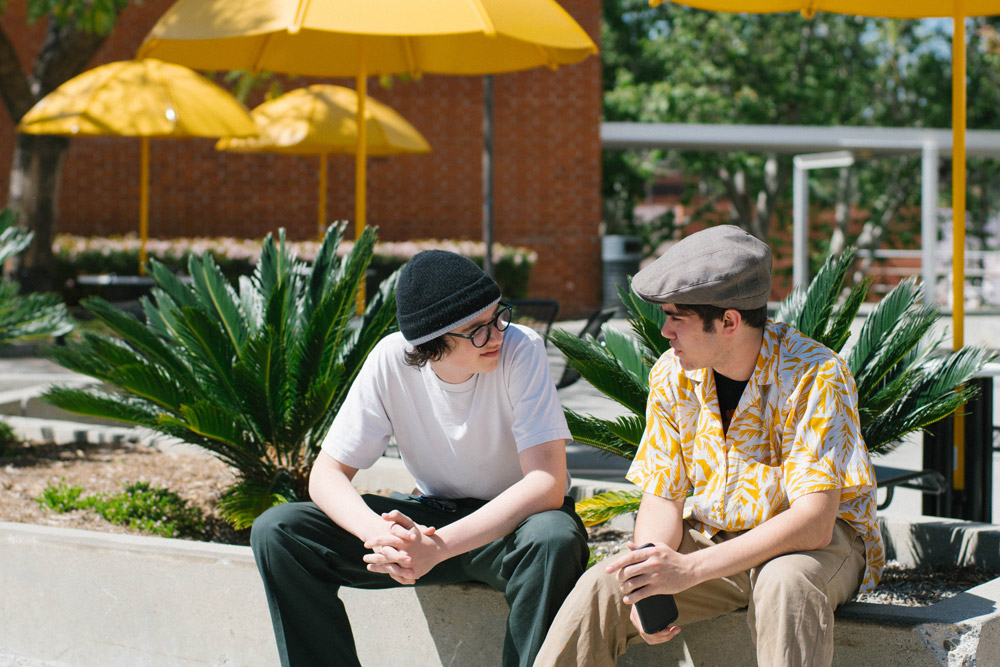 two kids talking to each other sitting on cement bench.